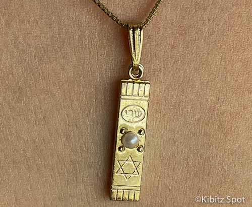 Mezuzah pendant on a gold chain.