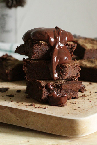 Homemade chocolate brownies stacked up and covered in hot fudge sauce