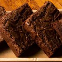 Four homemade brownies on a plate made from the ultimate gooey chocolate brownie recipe