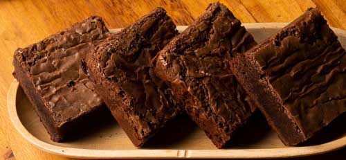 Four homemade brownies on a plate made from the ultimate gooey chocolate brownie recipe