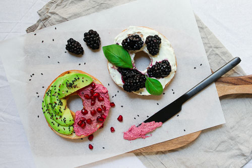 Pomegranate, avocado, and berries on separate a bagel