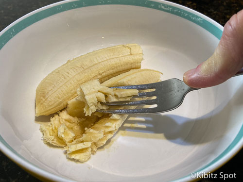 Mashed banana in a bowl is the fisrt step of our gluten free banana pancakes