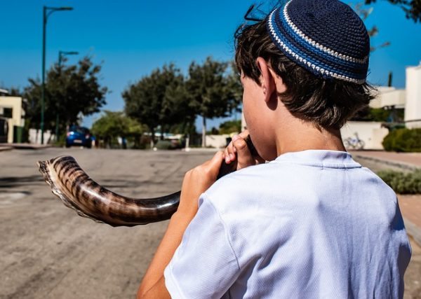 Boy blowing a shofar, a rams horn trumpet used in Jewish ceremonies