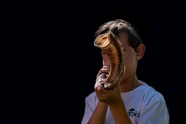 Boy blowing a shofar for a Jewish ceremony