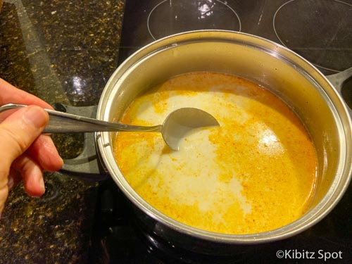 Gently stirring in coconut milk and soup stock to our tom kha gai recipe