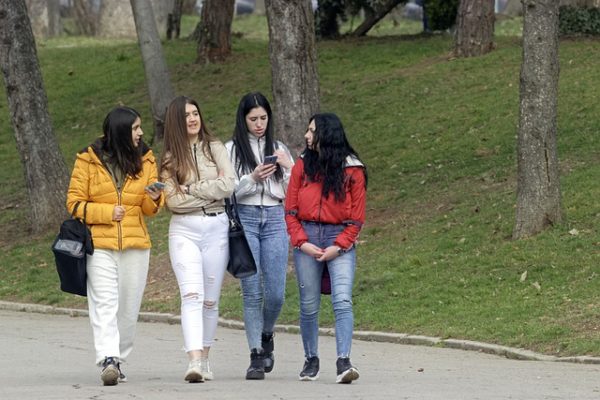 Four young women walking along a path, talking to each other
