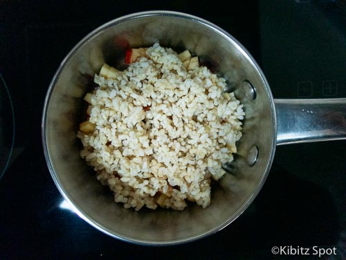 Rice added on top of apple and cinnamon in a pot