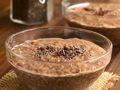 A chia chocolate pudding, topped with chia seeds and shaved chocolate, in a bowl on a woven mat.