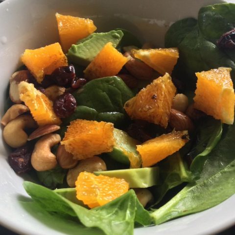 Finished salad with grapefruit, spinach, avocado, nuts, dried fruit, and balsamic vinegar