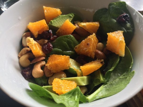 Finished salad with grapefruit, spinach, avocado, nuts, dried fruit, and balsamic vinegar