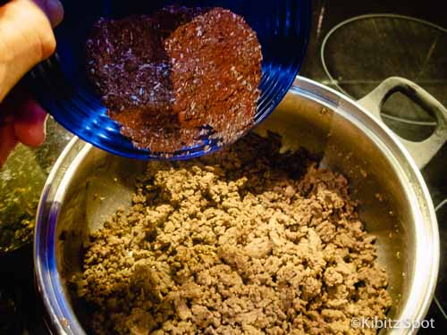 Spice mix being poured over ground beef