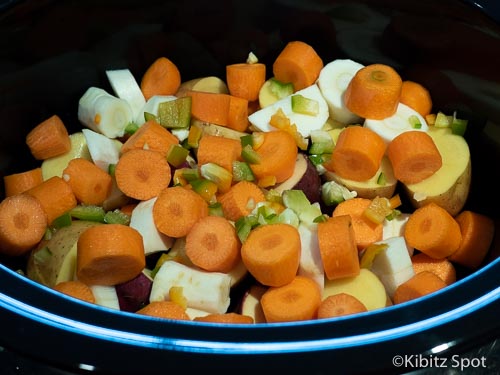 Carrots, celery, and bell pepper in a ceramic dish on a base of potato