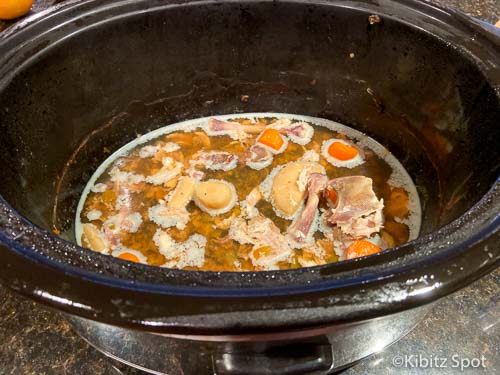 Chicken stock and vegetable scraps at base of crockpot to use as base for gluten-free chicken soup.