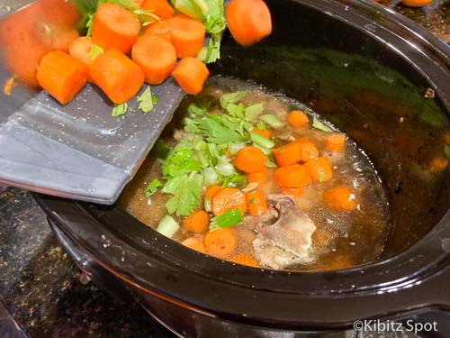 Adding the carrots and celery to the chicken stock and vegetables