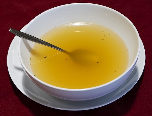 Clear chicken broth with vegetables drained out