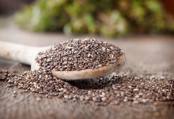 Black chia seeds on a wooden spoon