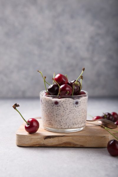 Chia pudding with cherry berries, in a glass on a grey surface