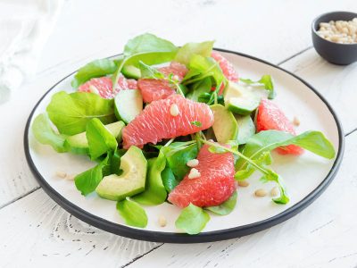 Finished spinach salad with grapefruit, avocado, chopped nuts, and balsamic vinegar