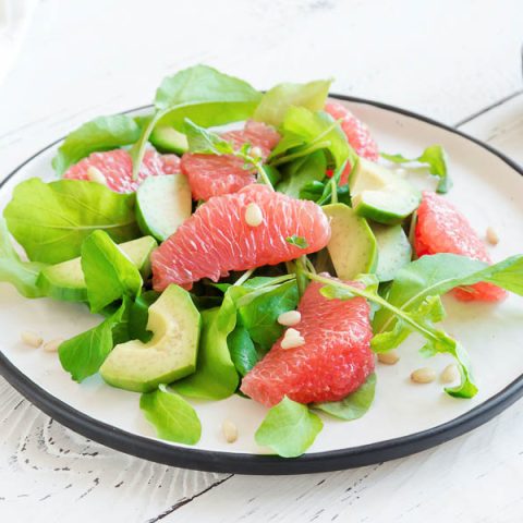 Finished spinach salad with grapefruit, avocado, chopped nuts, and balsamic vinegar