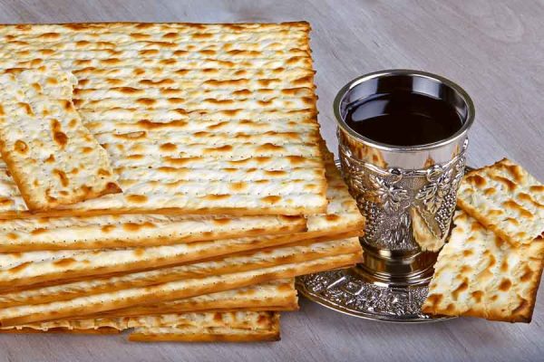 passover matzo with kiddush cup of wine on wooden table