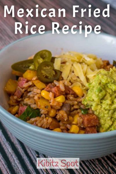 A bowl of Mexican fried rice topped with jalapenos, guacamole, and shredded cheese