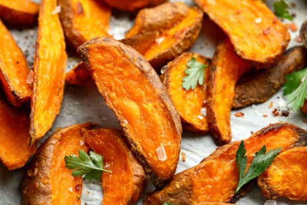 A tray of paleo sweet potato fries, topped with herbs, salt, and pepper