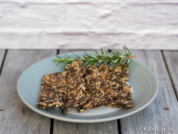 Gluten-free keto seed crackers on a plate with a twig of rosemary