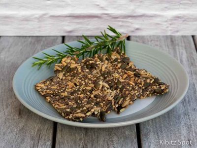 A plate of gluten free seeded crackers with a sprig of rosemary