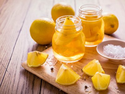 Jars of preserved lemon with the ingredients spread around on a wooden board