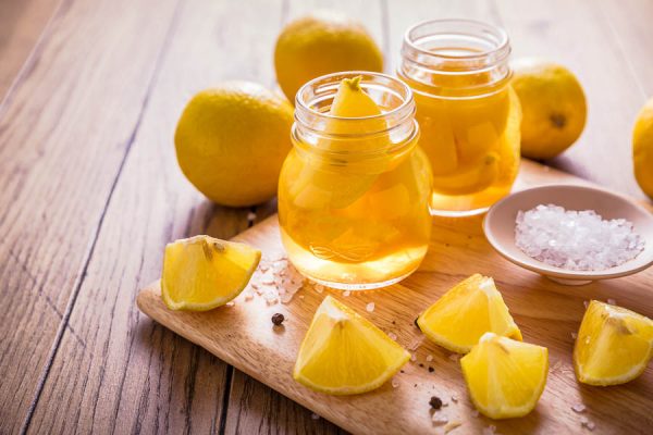 Jars of preserved lemon with the ingredients spread around on a wooden board