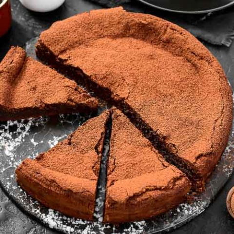 Gluten-free flourless chocolate cake on a plate missing one of eight slices.