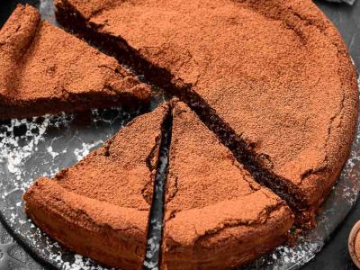 Gluten-free flourless chocolate cake on a plate missing one of eight slices.