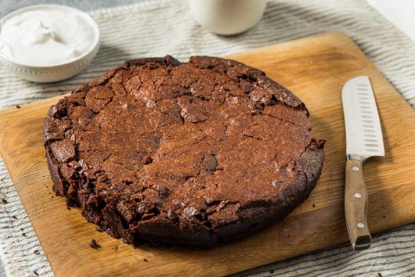 Gluten-free flourless chocolate cake just cooled, but not topped yet, on a wood board
