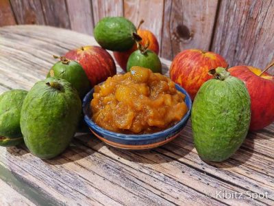 A serving bowl of sweet and tangy feijoa chutney with feijoas and apples in the background