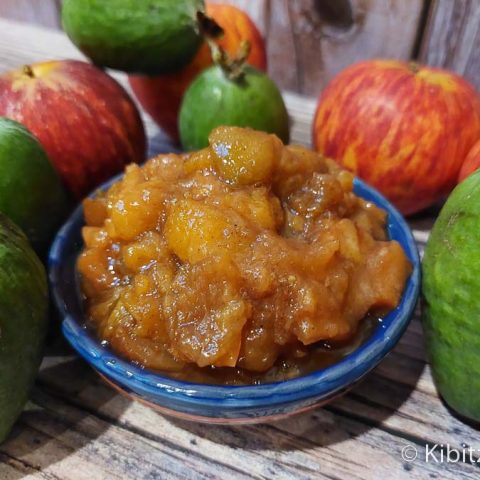 A serving bowl of sweet and tangy feijoa chutney with feijoas and apples in the background