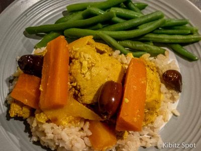 A plate of Moroccan preserved lemon chicken tagine on rice with a side of green beans