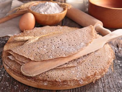 A stack of dairy free buckwheat pancakes / crepes with ingredients in the background