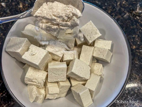 Easy Crispy Air Fryer Tofu Nuggets: Vegan and Gluten-Free 2 Gluten-free flour being added to tofu cubes