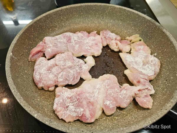 Chicken coated with flour frying in a pan