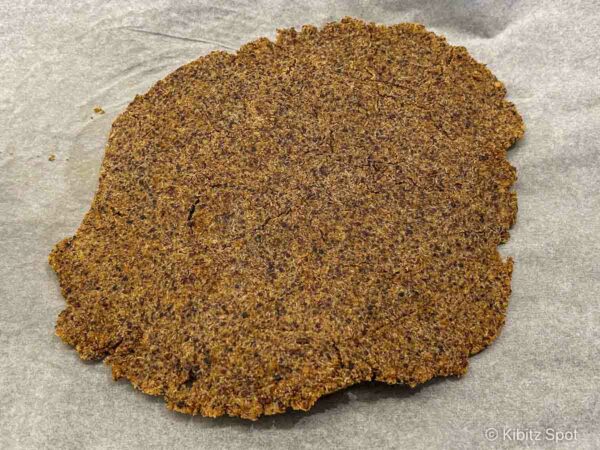 Gluten-free quinoa crackers on a baking sheet before being flipped and cut into individual pieces