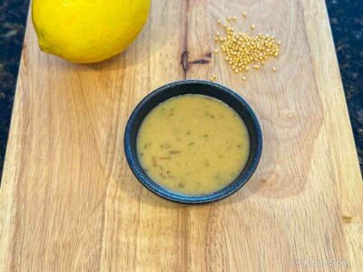A portion of lemon mustard dressing with to of its main ingredients - lemon and mustard