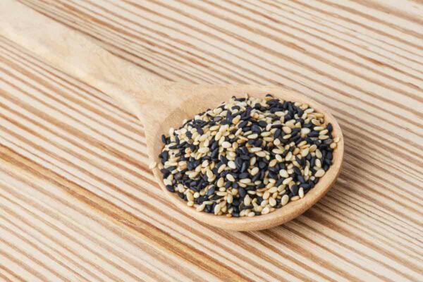 Three different colors of sesame seeds on a wooden spoon