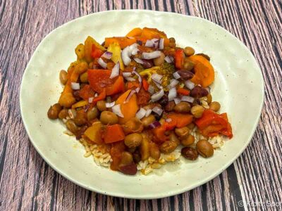 Vegetarian chili served over rice and topped with chopped onions and chili peppers