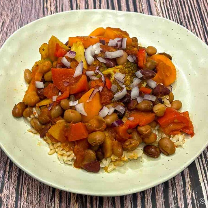Vegetarian chili served over rice and topped with chopped onions and chili peppers